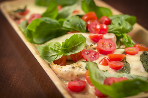 Grilled chicken topped with fresh basil and sliced tomatoes