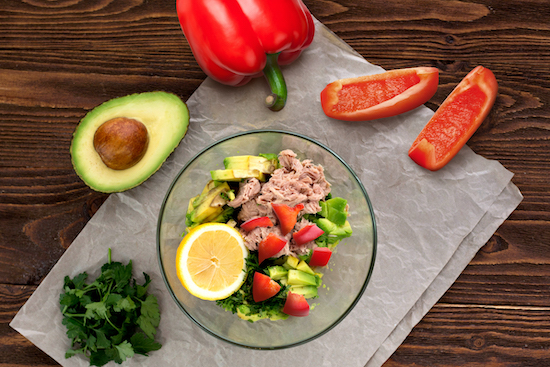 Green Salad  in glass bowl topped with tuna, avocado and bell pepper slices 