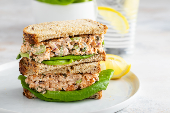 Sándwich de ensalada de salmón con hierbas en plato blanco 