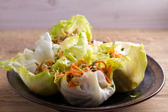 Wraps de pollo y lechuga en plato marrón sobre tabla de madera