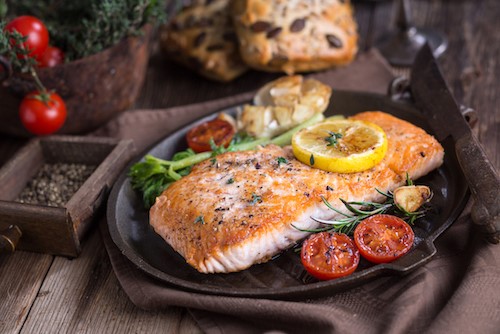 Lemon Herbed Salmon topped with lemon slice on black plate