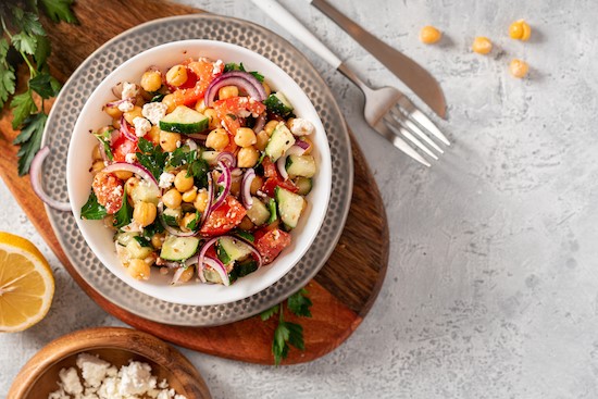Chopped chickpea salad in bowlon wood cutting board